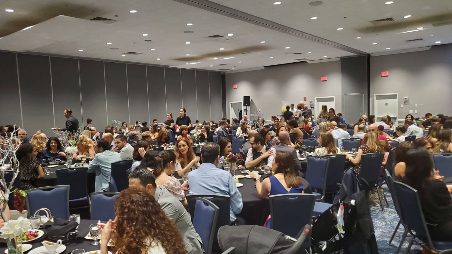 Supporters and community members seated at tables during a Global Community Logistics gathering