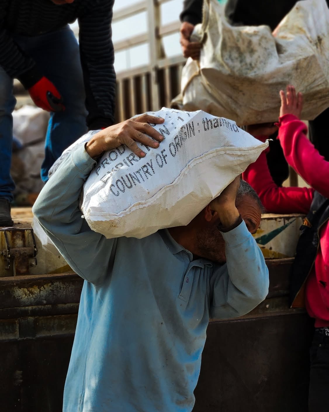 A worker carrying a sack of supplies down from a delivery truck